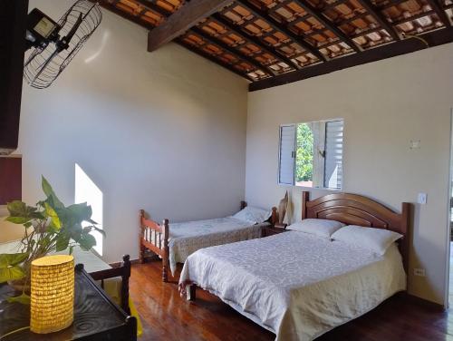 a bedroom with two beds and a window at Carneiro Caiçara chalés- Casinhas aconchegantes em Ubatuba in Ubatuba