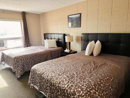 ein Hotelzimmer mit zwei Betten und einem Fenster in der Unterkunft Beaverlodge Motor Inn in Beaverlodge