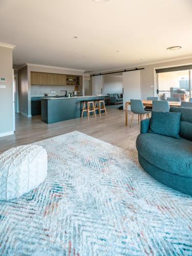a living room with a couch and a kitchen at Coastal Bliss Retreat Elegant Beachside Escape at Hawley Beach in Port Sorell