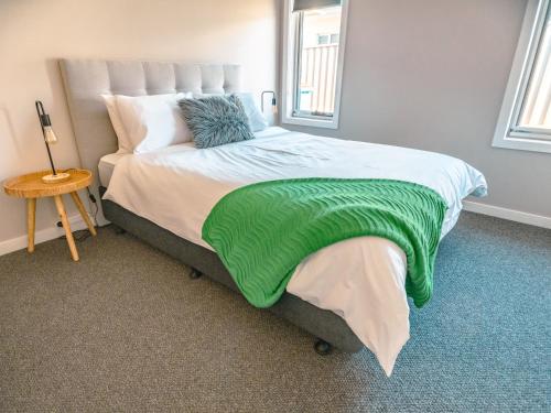 a bedroom with a bed with a green blanket on it at Coastal Bliss Retreat Elegant Beachside Escape at Hawley Beach in Port Sorell