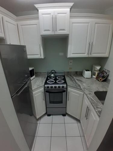 a small kitchen with a stove and white cabinets at beach 1 bedroom 23 in Ocho Rios