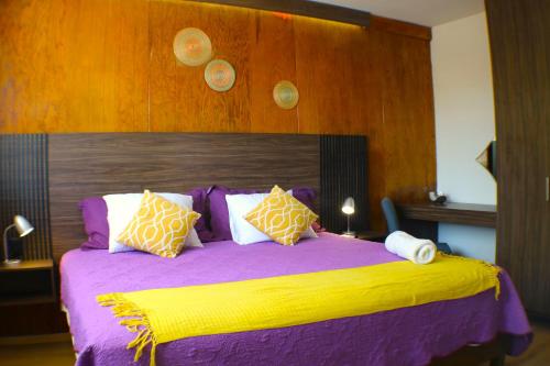 a bedroom with a bed with purple sheets and pillows at Pino Apartment in Oaxaca City