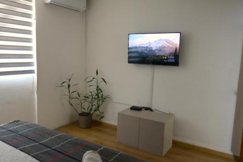 a television hanging on a wall in a bedroom at Pino Apartment in Oaxaca City