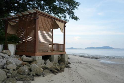a wooden building on a beach with rocks at Ombak Villa Langkawi in Pantai Cenang