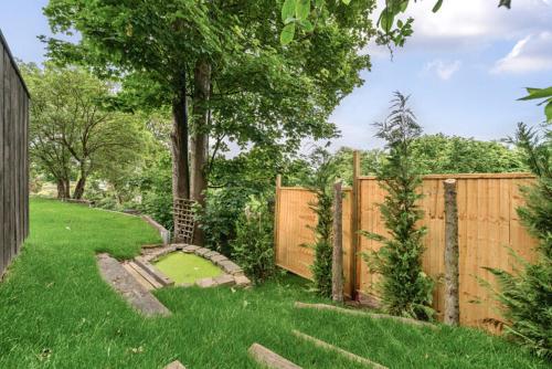 a backyard with a wooden fence and a green yard at The Ridge London - Luxury Designer Villa with hot tub and sauna, Bexley borough of London in London