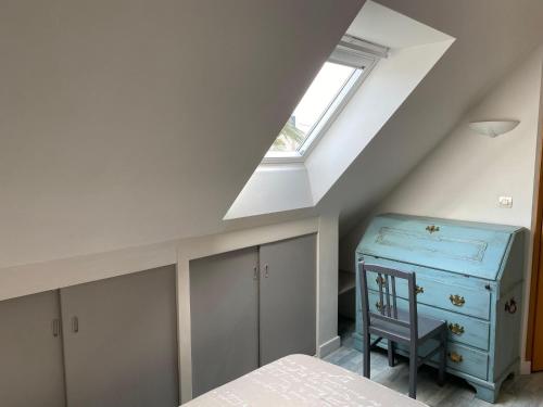 une chambre mansardée avec une commode bleue et une fenêtre dans l'établissement Holiday Home Perros-Guirec Pink Granite Coast, à Perros-Guirec