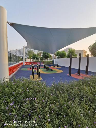 a park with benches and a large white canopy at Jupiter Saadiyat Beach New York Abu Dhabi university Studio Apartment in Abu Dhabi