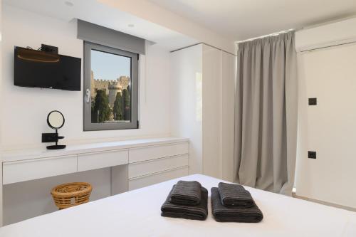 a white bedroom with a bed with two black towels at Castelo View Luxury apt in Rhodes Town