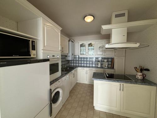 une cuisine avec des armoires blanches et une laveuse et une sécheuse dans l'établissement Appartement T3 avec balcon et garage aux Sables-d'Olonne - FR-1-197-185, à Les Sables-dʼOlonne