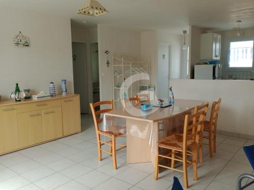 une cuisine avec une table et des chaises dans une pièce dans l'établissement Charmante maison pour 4 personnes avec terrasse, à 1,8 km de la plage et proche des commodités - FR-1-357-76, à Saint-Vincent-sur-Jard
