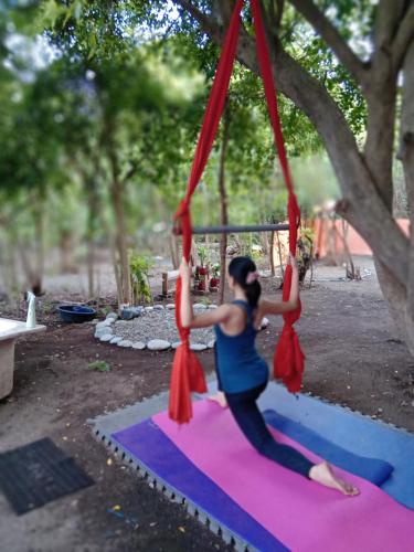a woman doing yoga on a swing in a tree at SECLUDED GLAMPING YOGA SAMADHI fan 2 kubos 8 pax in Rimus
