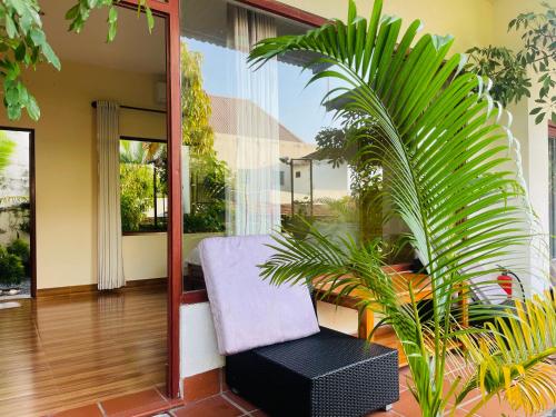 a room with a chair and a palm plant at Mui Ne Garden Hotel and Kite School in Mui Ne