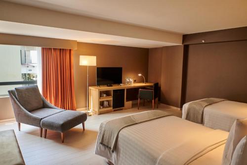 a hotel room with a bed and a chair and a desk at Casa Andina Premium Golf Los Incas in Lima