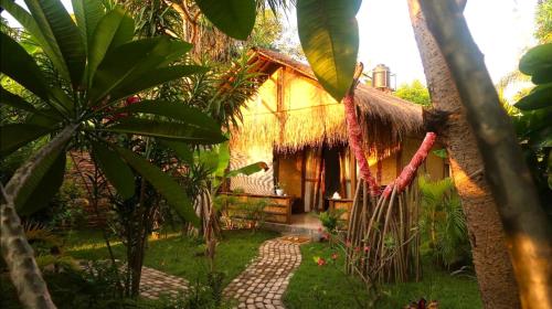 una casa con techo de paja y un camino delante en UTOPIA, en Gili Air