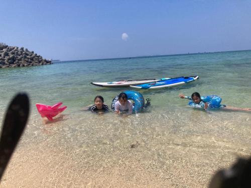 three children laying in the water at the beach at ZARATAN in Motobu