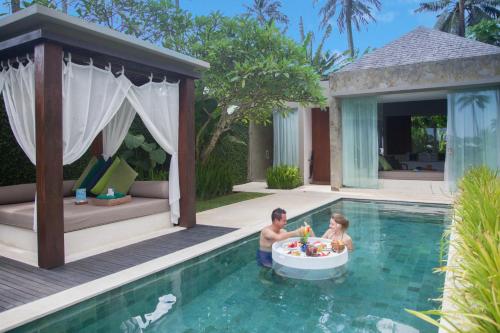 a man and a child playing in a bath tub in a pool at Candi Beach Resort & Spa in Candidasa