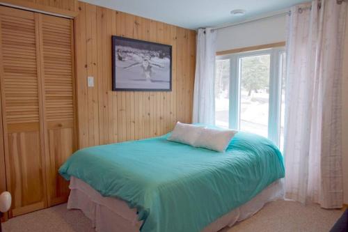 a bedroom with a bed in front of a window at Chalet familial et SPA à proximité du Mont Orford in Orford