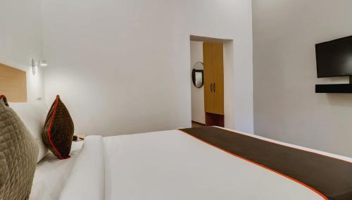 a bedroom with a white bed and a flat screen tv at Super Townhouse Gandhi Hall in Indore