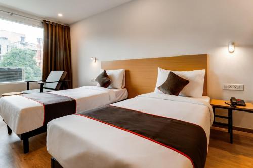 a hotel room with two beds and a window at Super Townhouse Gandhi Hall in Indore