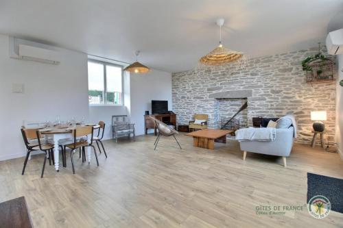 un salon avec une table et un mur en pierre dans l'établissement La grande plage, à Saint-Cast-le-Guildo