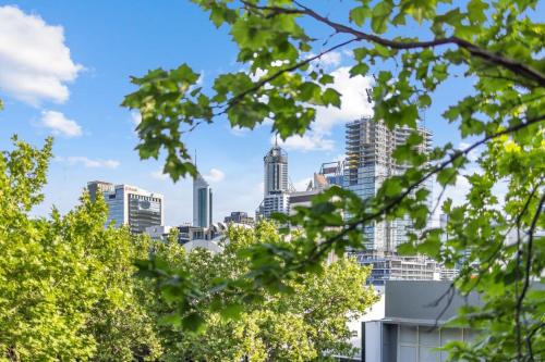 a view of the melbourne city skyline through trees at Exclusive Northbridge Apt w Wi-Fi Pool in Perth