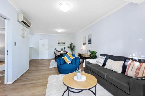 a living room with a couch and a table at Exclusive Northbridge Apt w Wi-Fi Pool in Perth