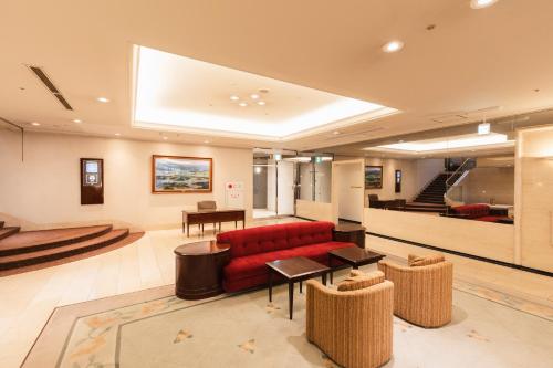 a living room with a red couch and a table at Hotel Sunroute Niigata in Niigata