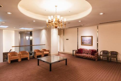 a waiting room with a couch and chairs and a chandelier at Hotel Sunroute Niigata in Niigata