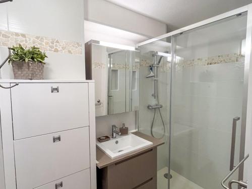 une salle de bain blanche avec un lavabo et une douche dans l'établissement T2 avec terrasse à Saint Cyprien - Plage, Piscine et Parking - FR-1-753-23, à Saint-Cyprien