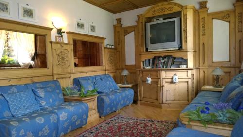 uma sala de estar com sofás azuis e uma televisão em LA FELCE Bed & Breakfast em Carisolo