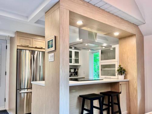 a kitchen with two stools at a counter with a refrigerator at Chalet tout inclus avec SPA près du Mont Orford in Orford