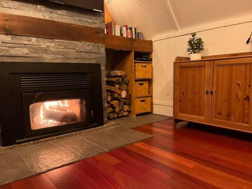 a living room with a fireplace and a wooden floor at Chalet tout inclus avec SPA près du Mont Orford in Orford
