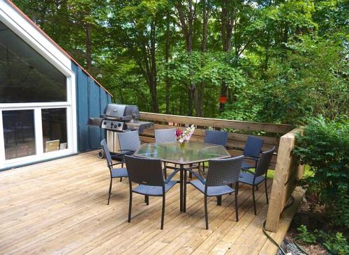 a patio with a table and chairs on a deck at Chalet tout inclus avec SPA près du Mont Orford in Orford