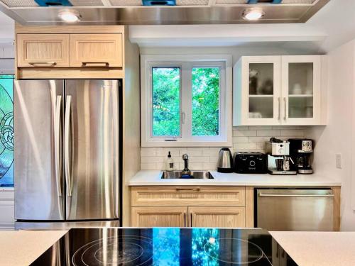 a kitchen with a stainless steel refrigerator and cabinets at Chalet tout inclus avec SPA près du Mont Orford in Orford
