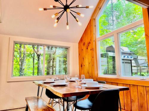 a dining room with a table and some windows at Chalet tout inclus avec SPA près du Mont Orford in Orford