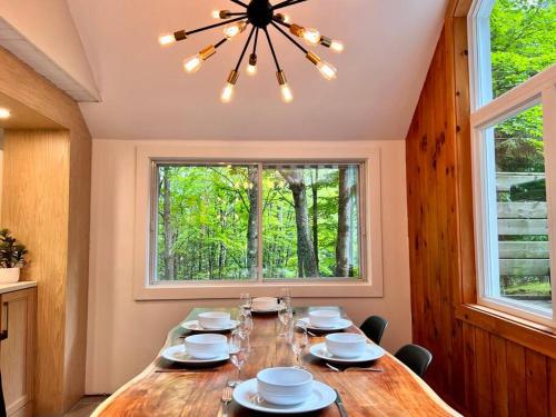 a dining room with a table with chairs and a window at Chalet tout inclus avec SPA près du Mont Orford in Orford