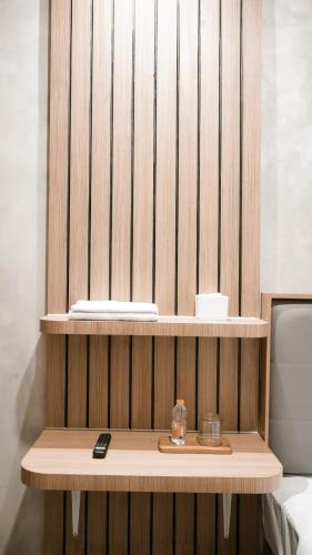 a wooden shelf with a remote control on a table at Omni Rooms by Sinergi in Semarang