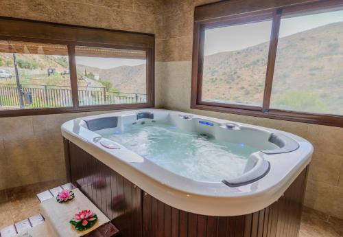 a large bath tub in a room with windows at Casas Rurales Picachico in Laroya