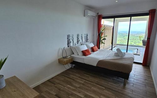 a bedroom with a bed and a large window at Les Suites DNJ Martinique in Le François