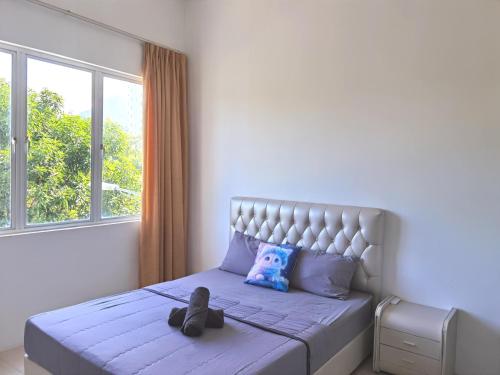 Un osito de peluche sentado en una cama en un dormitorio. en LANGKAWI MODERN FAMILIES SUITE @ SIMFONI KUAH, en Kuah
