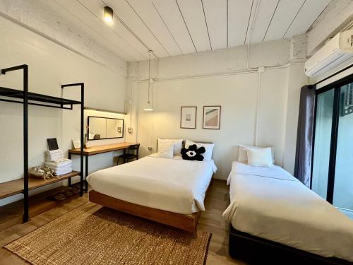 a bedroom with two beds and a desk and a window at The51Hometel in Chiang Mai