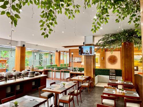 a restaurant with wooden tables and chairs and trees at Hemangini Hotel Bandung in Bandung