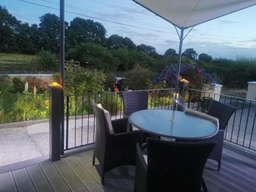a table and chairs on a deck with an umbrella at Tranquil unit close to Kells in Kilkenny