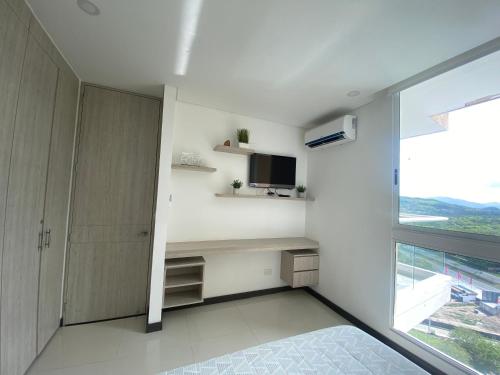 a bedroom with a bed and a tv and a window at Modern well-equipped 4 PPL condo/5 MIN beach walk in Santa Marta