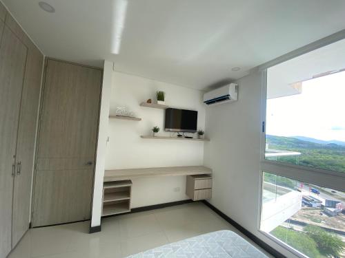 a room with a desk and a tv and a window at Modern well-equipped 4 PPL condo/5 MIN beach walk in Santa Marta