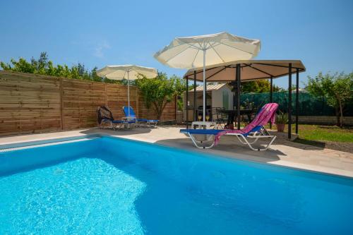 una piscina con dos sillas y sombrillas en Jokos House, en Rodas