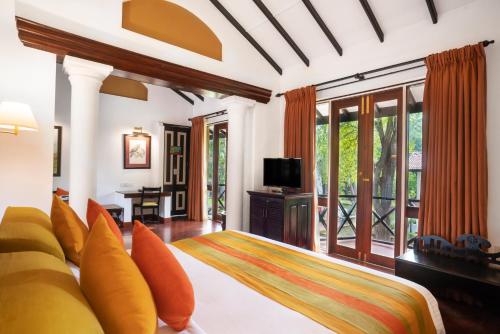 a bedroom with a bed and a tv and a balcony at Cinnamon Lodge Habarana in Sigiriya