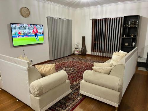 a living room with two couches and a flat screen tv at Kathmandu Farmstay - Pool Table, Ping Pong, Bicycles, PlayStation, Netflix, close to Bathurst and Mayfield Garden in Brewongle