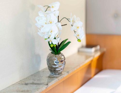a vase filled with white flowers sitting on a counter at PLAZA INN Blankenburg Ditzingen, Sure Hotel Collection in Ditzingen