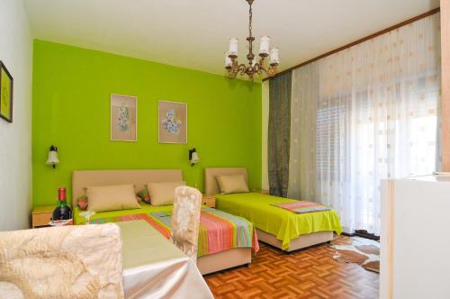 a green bedroom with two beds and a chair at Guesthouse Lanca in Tivat
